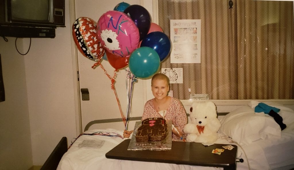 A childhood leukemia survivor celebrates finishing treatment with a cake and balloons. 